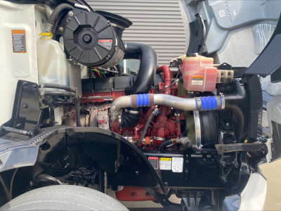 Mack AN42T engine bay showing red diesel engine with blue silicone hose clamps and multiple fluid reservoirs.