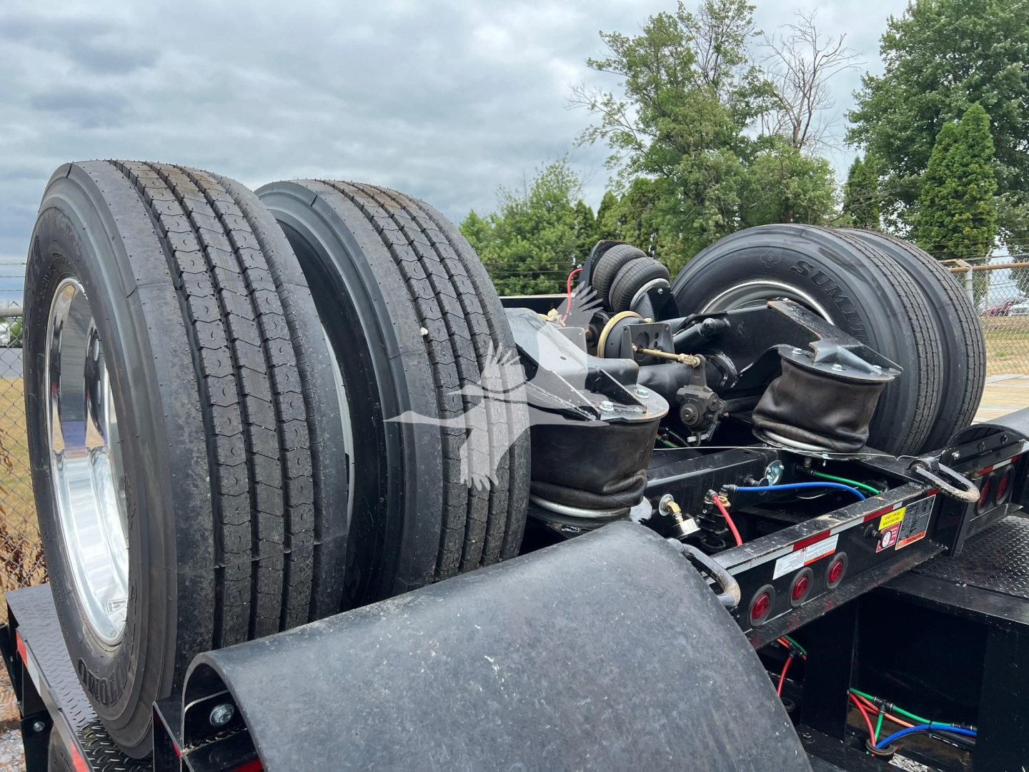 Trailer with dual rear axles and spare tires showing suspension components and wiring on a lowboy trailer.