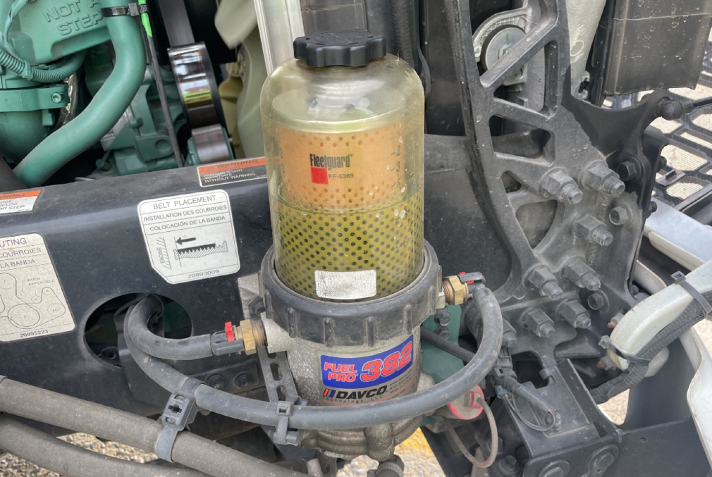 Engine bay showing hydraulic or fuel filter canister labeled 'Fuel 3B' with Dagvosmart? surrounding hoses and a yellow translucent reservoir