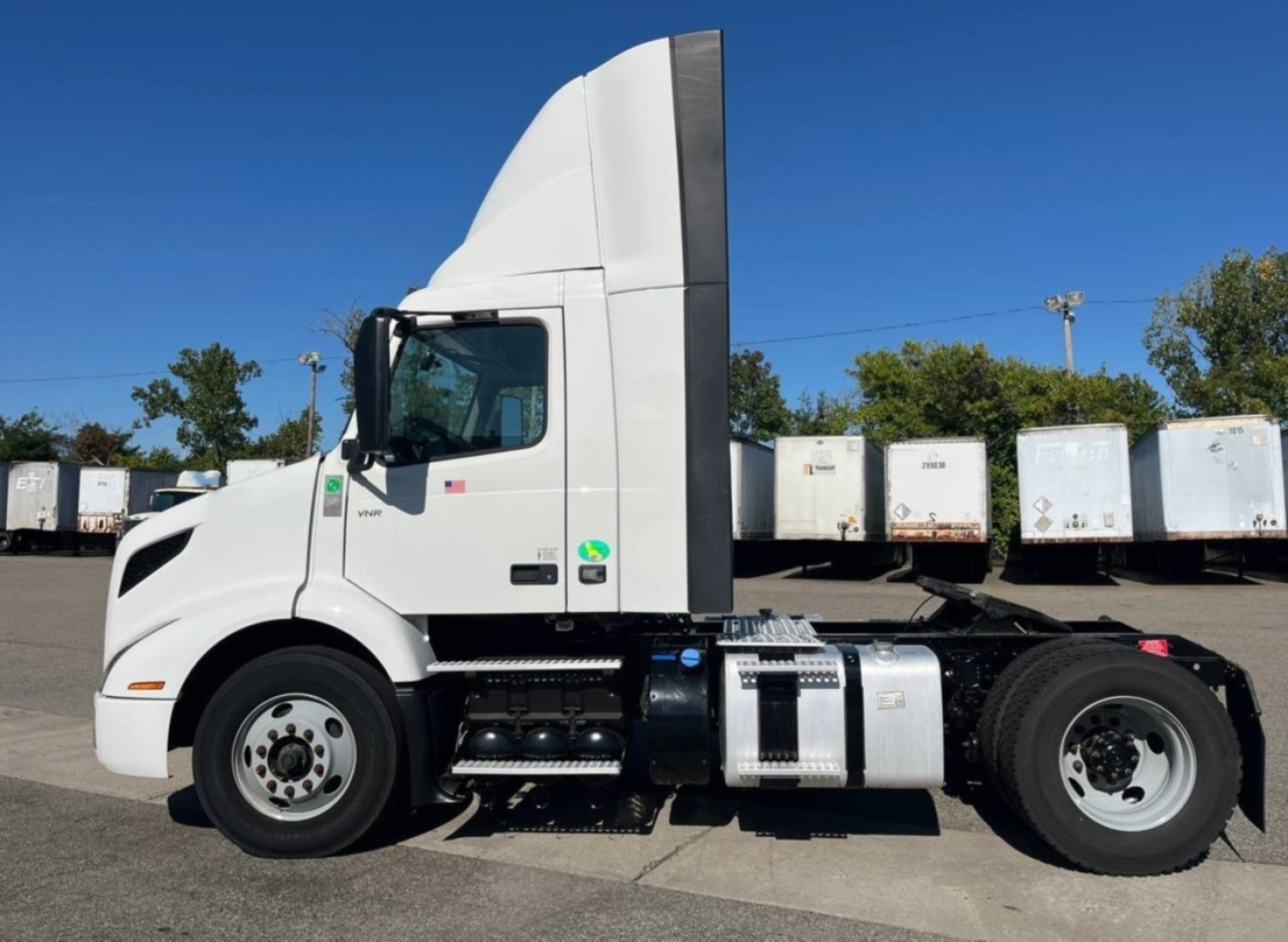 truck side view showing Volvo VNR300 4x2 day cab with white cab and sleeper, side fuel tanks, and rear wheels