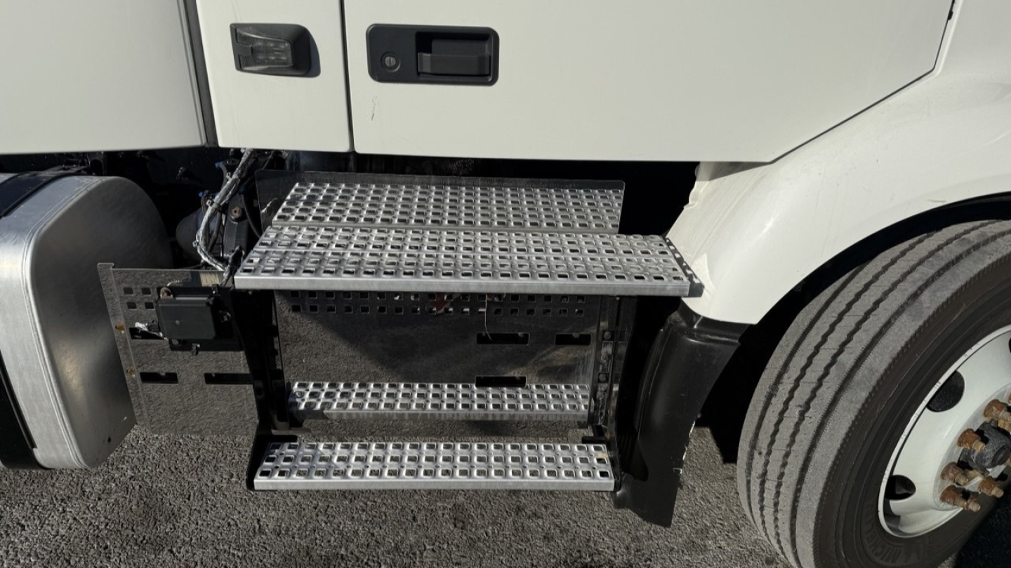 Volvo VNR300 day cab sideview showing metal diamond-plate steps and front wheel well.