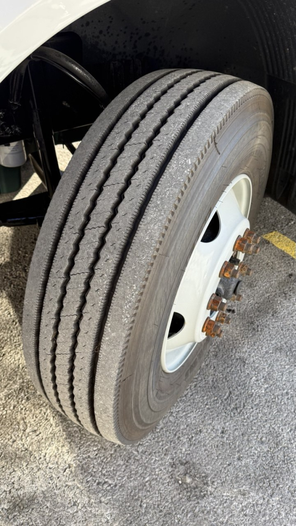 Front wheel and tire of a Volvo VNR300 day cab showing dual tires with wheel hub and lug nuts, vehicle frame and suspension components visible.