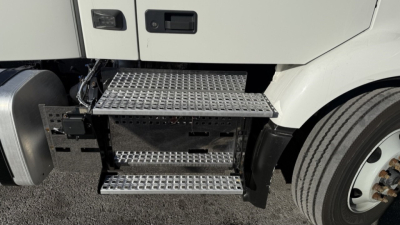 Volvo VNR300 day cab sideview showing metal diamond-plate steps and front wheel well.