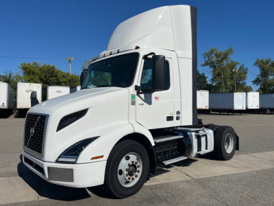 Volvo VNR300 day cab tractor showing side view with aerodynamic hood, single axle, white paint, tall sleeper cab, fuel tanks, and front grille badges visible.