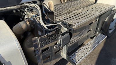 Truck cab step and engine bay area showing perforated steel steps and adjacent components in a Volvo VNR300 4x2 Day Cab.