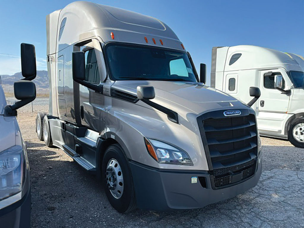 Freightliner Cascadia126 tractor-trailer cab in a parking lot showing front grille with Freightliner emblem and headlights.