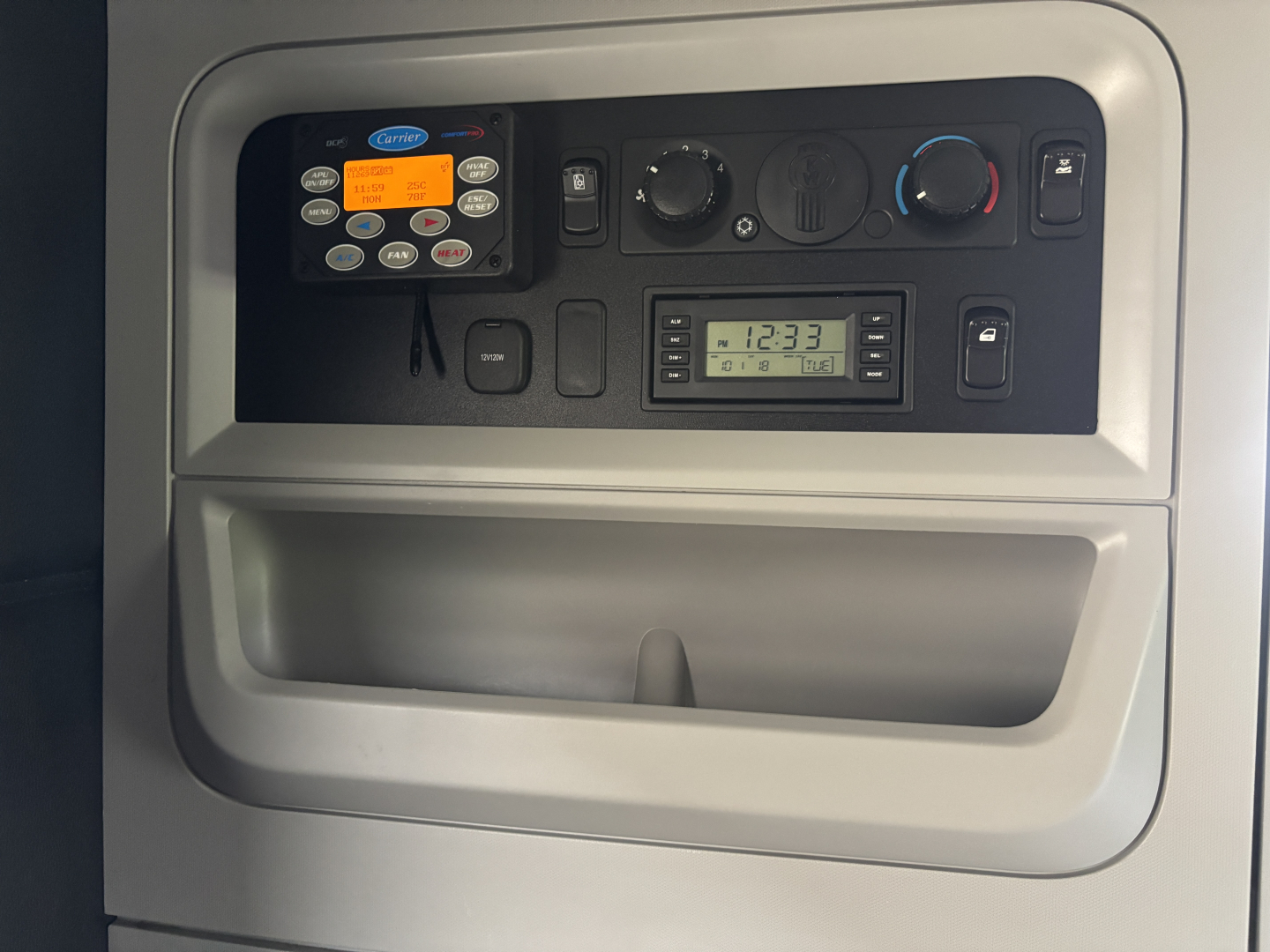 Kenworth T680 dash panel showing control module, climate knobs, and digital clock inside cab area.