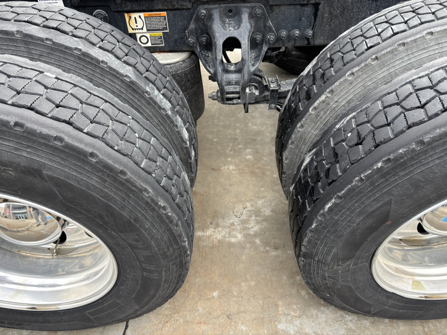 Kenworth T680 dual rear axles with tires and suspension visible, undercarriage components in view.