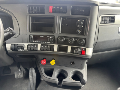 Dashboard interior of a 2023 Kenworth T680 showing switches, vents, cup holders, and control panels.