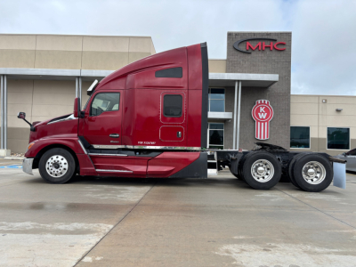 Kenworth T680 tractor in red color, side view showing cab with sleeper, rear axles, and wheels