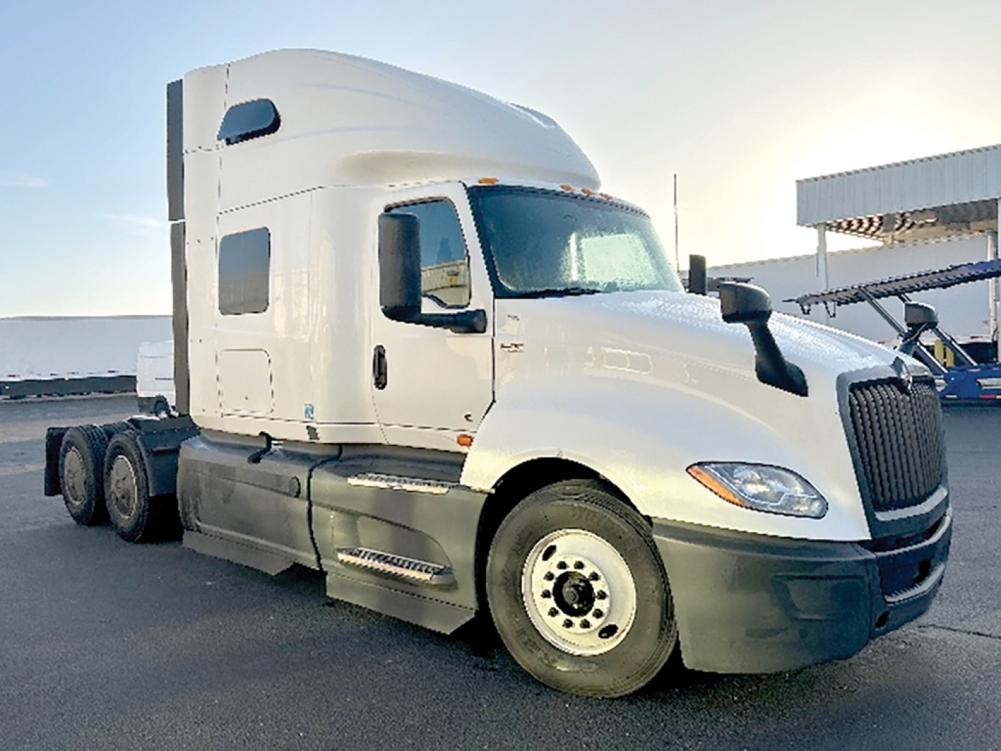 Truck cab with sleeper shows International LT625 in-service/. The image displays a white 3-axle tractor with a high-rise sleeper and dual rear wheels, front grille, and side mirrors.