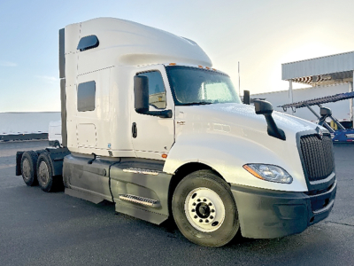 Truck cab with sleeper shows International LT625 in-service/. The image displays a white 3-axle tractor with a high-rise sleeper and dual rear wheels, front grille, and side mirrors.
