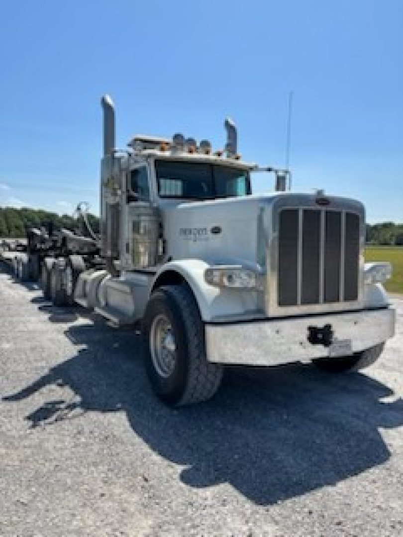 Peterbilt 389 day cab truck in serviceable condition, front view with grille, headlights, large bumper, visor, air cleaners, and dual exhaust stacks.