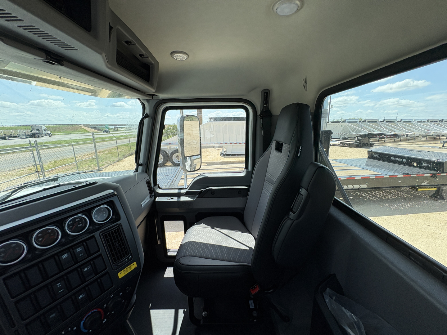 Truck cab interior showing dashboard controls and passenger seat with window view to exterior lot.