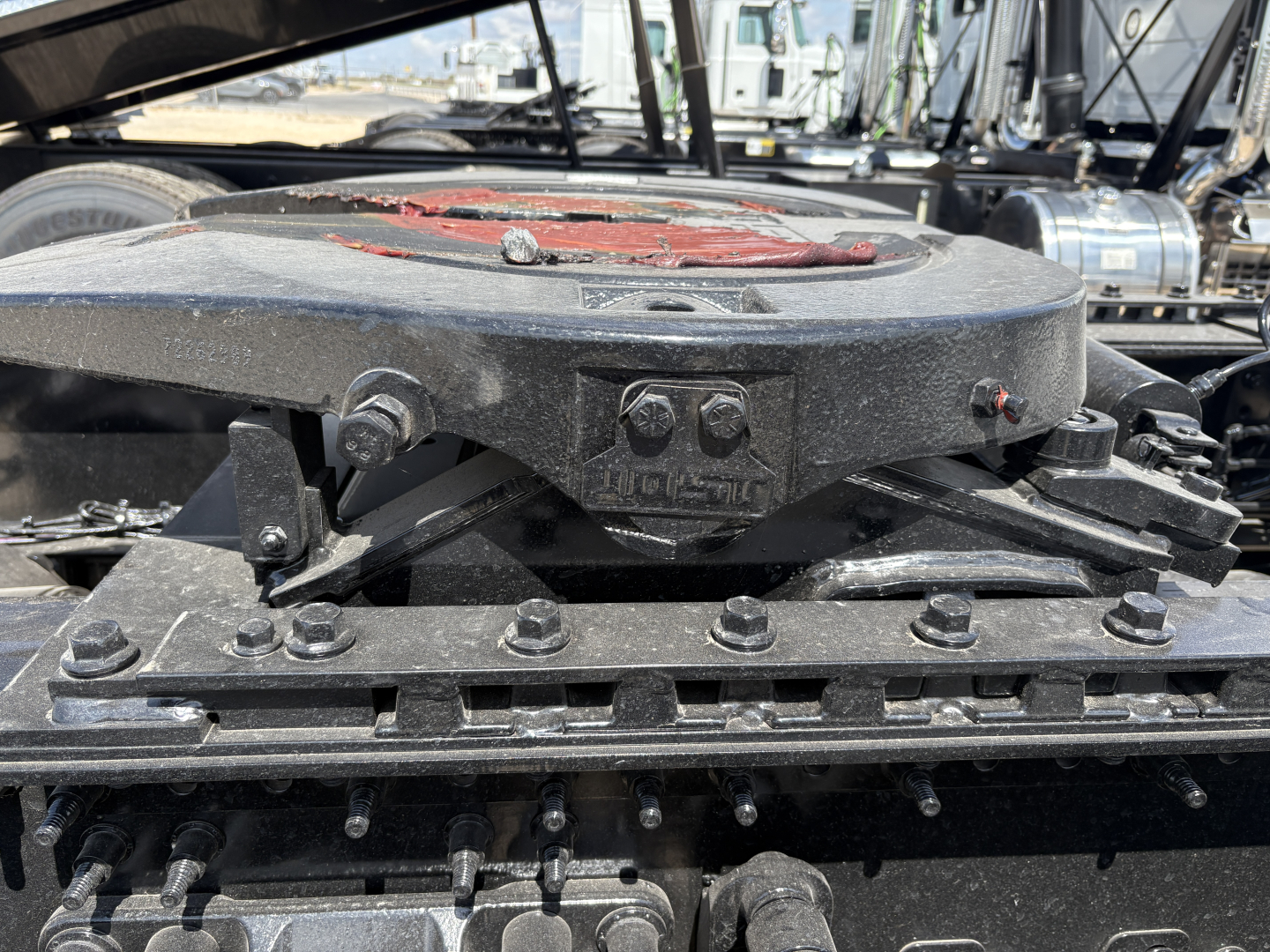 Tractor-trailer engine bay showing top of air reservoir and mounting bolts with label reads ‘MIC 11’ on black metal components.