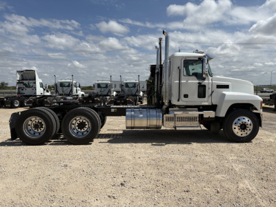 Mack PI64T conventional daycab tractor side view showing cab, exhaust stacks, chrome fuel tanks, and dual rear axles.