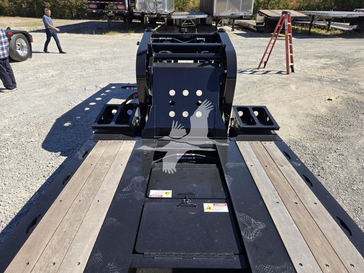 Trailer hitch area of a Fontaine 55 Lcc hydraulic flip lowboy trailer showing deck with wooden planks and hydraulic flip mechanism.
