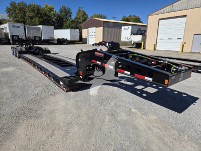 Trailer frame showing hydraulic flip in lowboy configuration with black finish and red and white safety markings.
