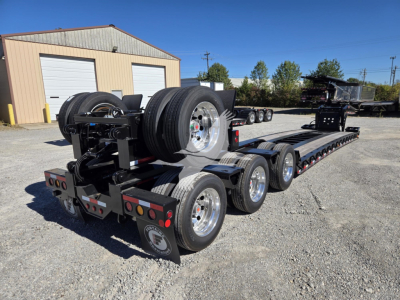 Lowboy trailer with multiple axles and spare tires on a Fontaine 55 Lcc hydraulic flip system, side view showing dual rear axles and long transport deck.