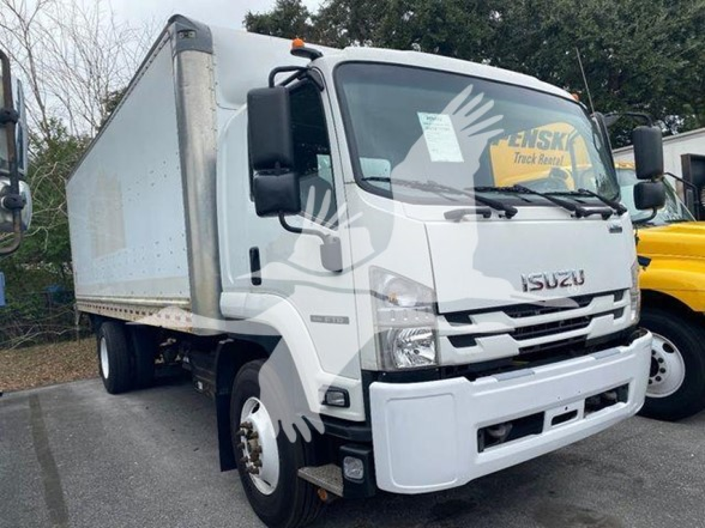 Isuzu FTR box truck from 2018 in-view front-left angle showing cab and cargo box, headlights, grille, Isuzu emblem, and side mirror.