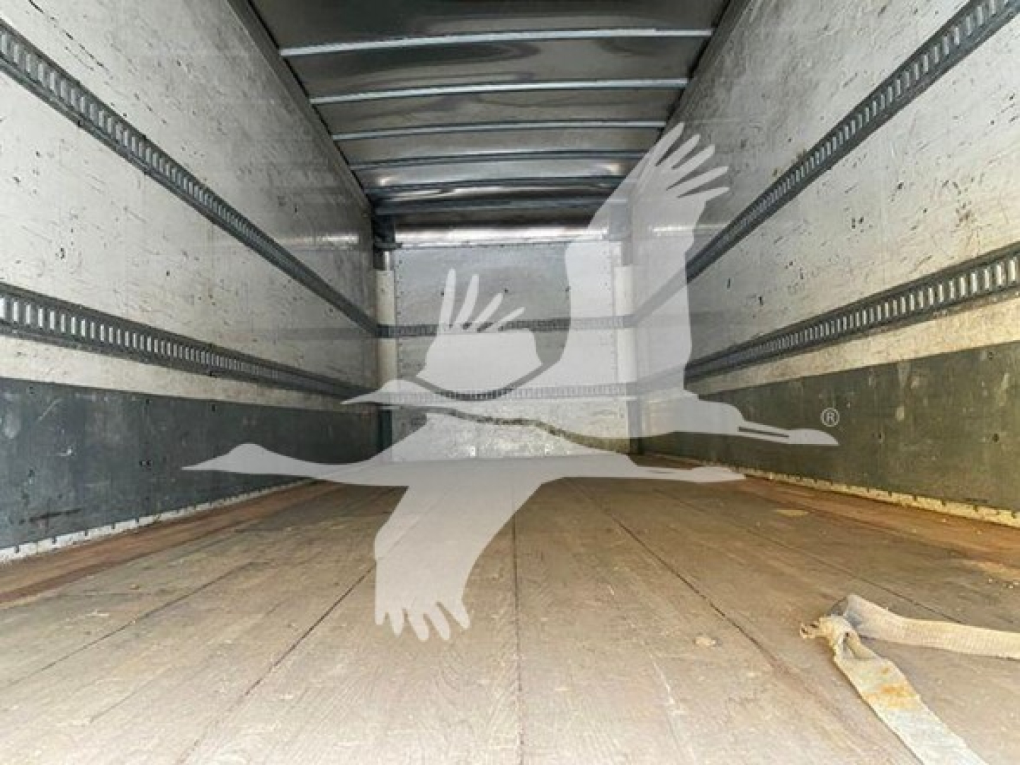 Isuzu box truck interior showing empty cargo area with wooden floor and metal side rails. watermark of a flying bird logo obstructs center.