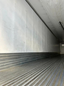 Trailer interior showing aluminum sidewall and ribbed floor of a refrigerated trailer.