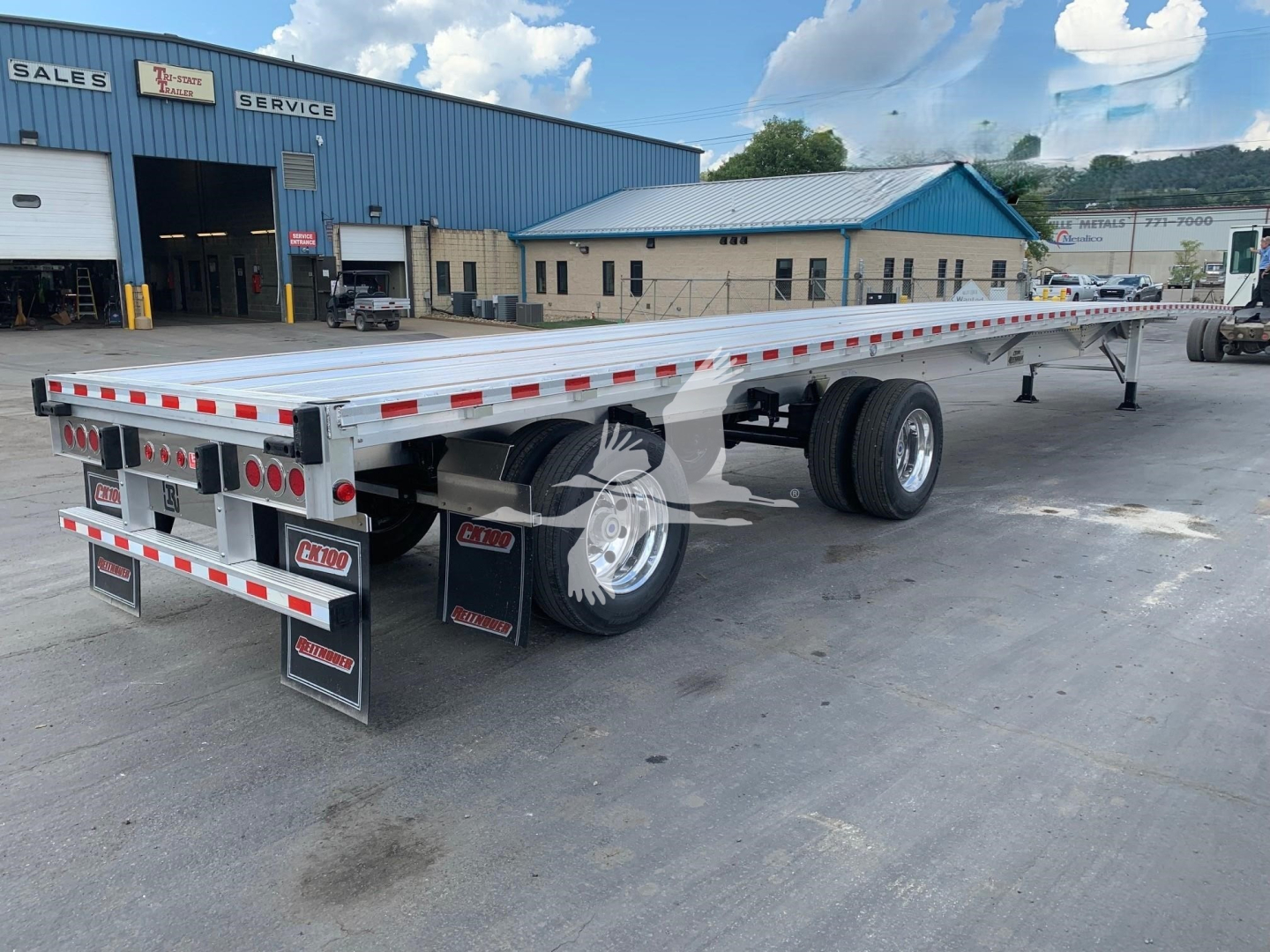 Trailer side view showing a flatbed trailer with dual rear axles and red/white reflective tape along the edges.
