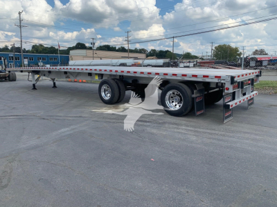Flatbed trailer showing tandem axle with aluminum deck, side rails, rear ramps, and Reflective tape. Sticker labels and structural components visible.