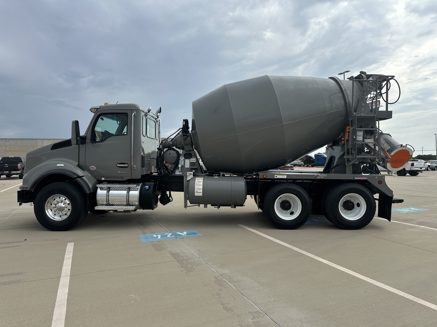 Concrete mixer truck with a gray cab and large cement mixer drum in a parking lot.