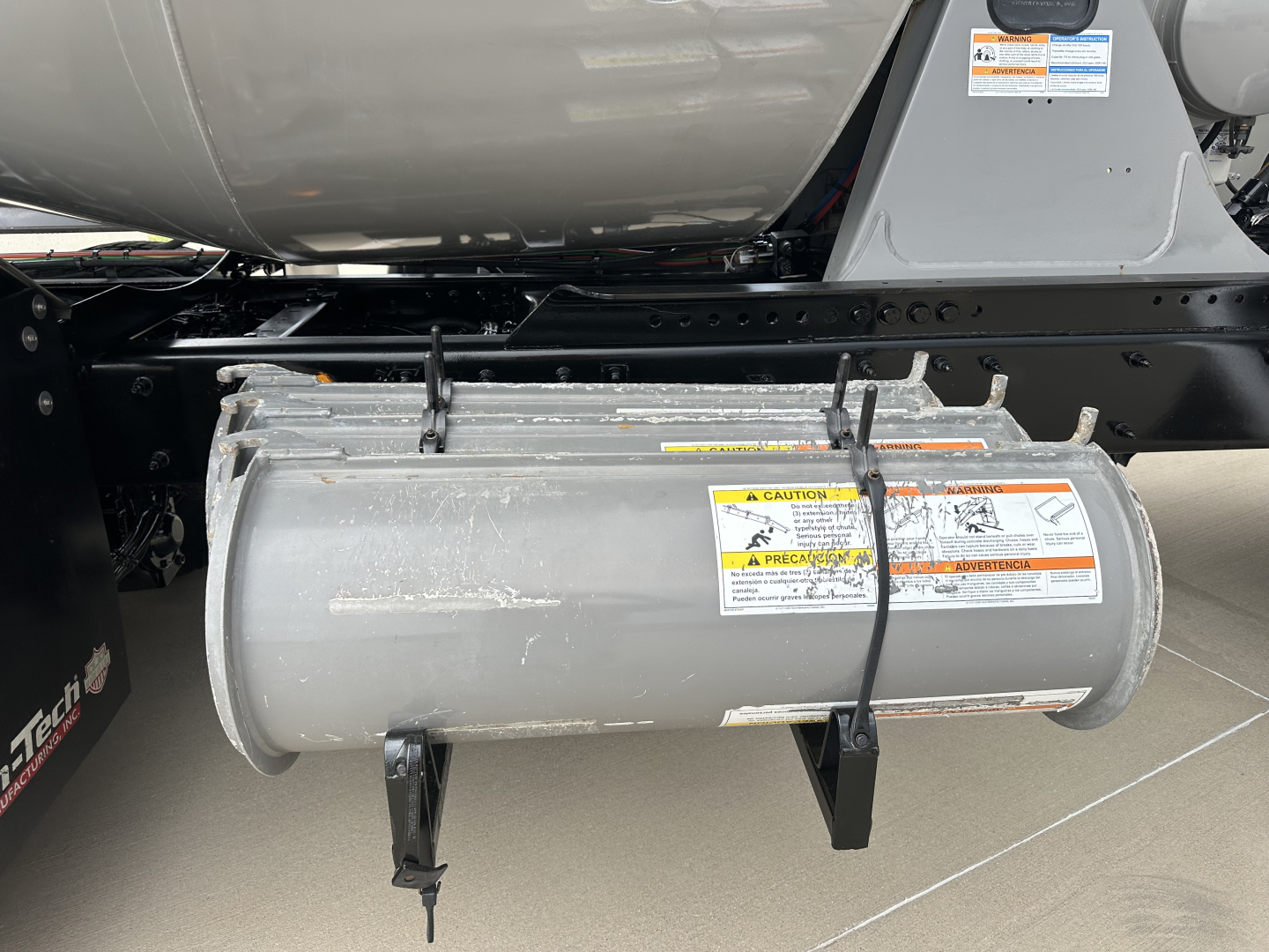 Kenworth T880 mixer truck undercarriage showing cylindrical fuel tank with warning labels and mounting brackets.