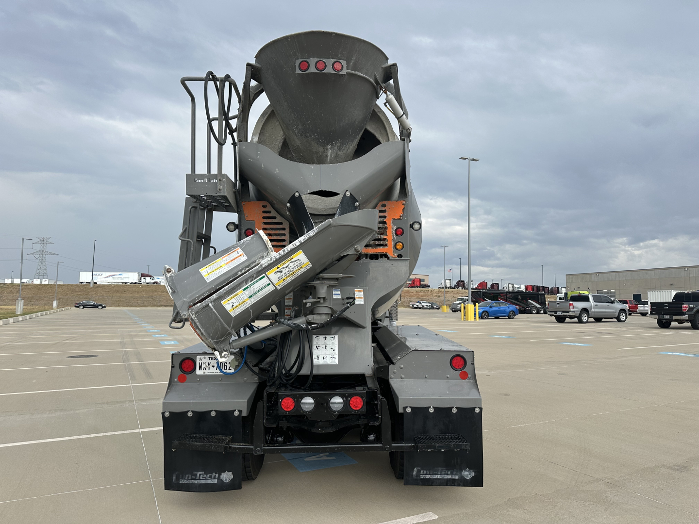Kenworth T880 mixer truck rear view showing cement mixer chute and warning labels