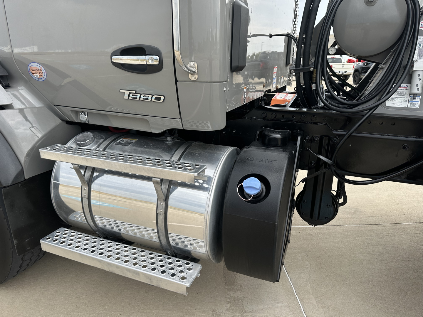 Kenworth T880 truck side showing fuel/saddle tank and steps with 'T880' badge on cab and various hoses.