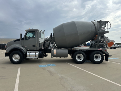 Concrete mixer truck with a gray cab and large cement mixer drum in a parking lot.