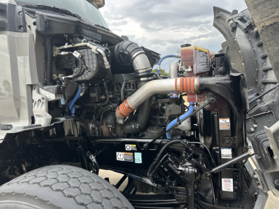 Kenworth T880 engine bay showing intake hoses, coolant reservoir, and hydraulic lines in front compartment.