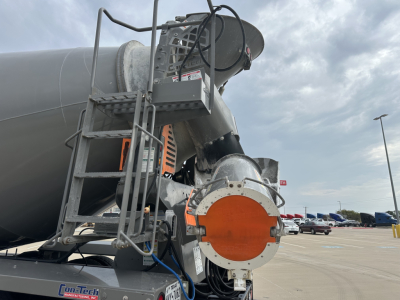 Kenworth T880 mixer truck component with orange circular cover and metallic chute in view.