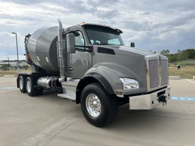 Kenworth mixer truck 2026 model in gray, front-right view, with mixer drum and chrome exhaust stacks visible.