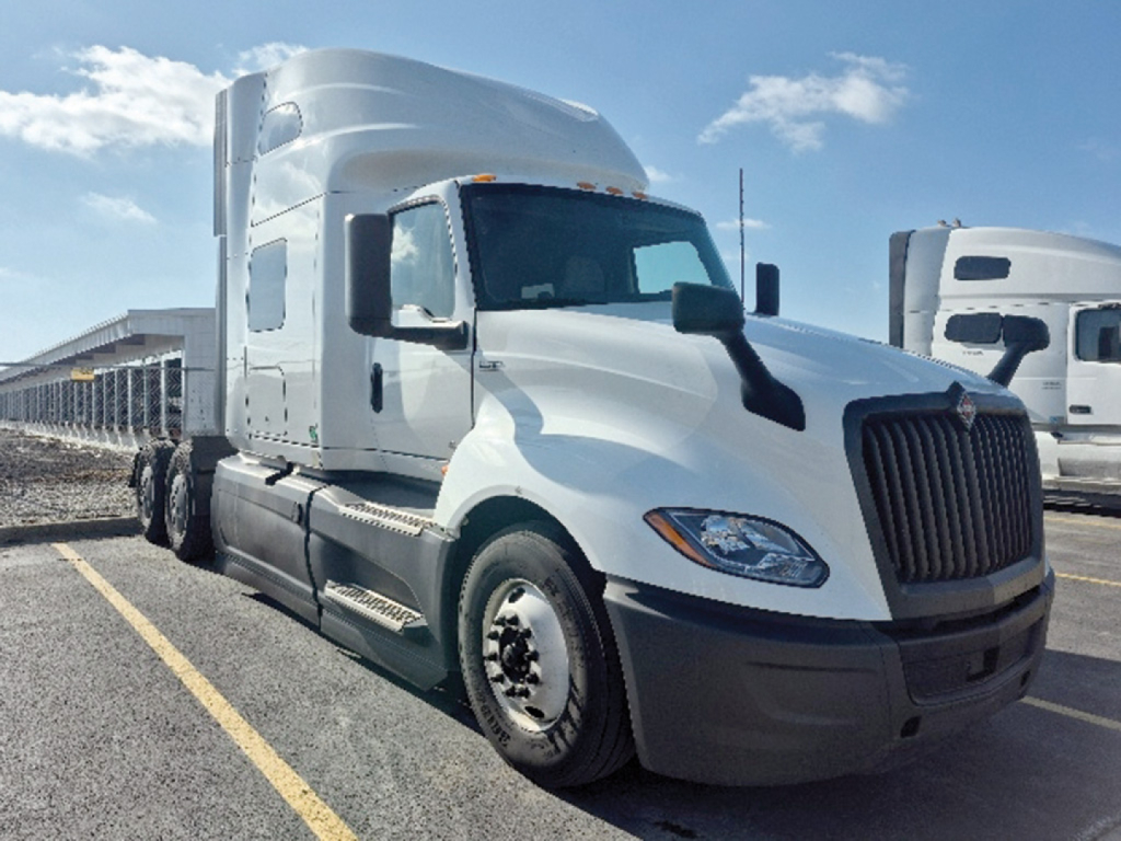 Truck cab in a parking lot showing International LT625 with white exterior and sleeper cab, front view.
