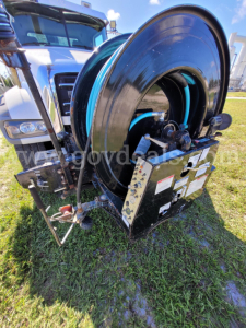 Front view of a Mack GU713 wiring and hose reel unit with large black hose reel and control panel.