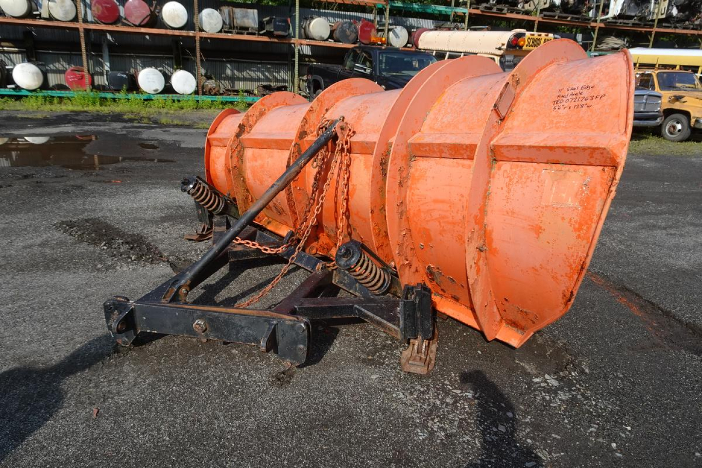Dump truck accessory showing orange snowplow or spinner attachment with springs and mounting frame.