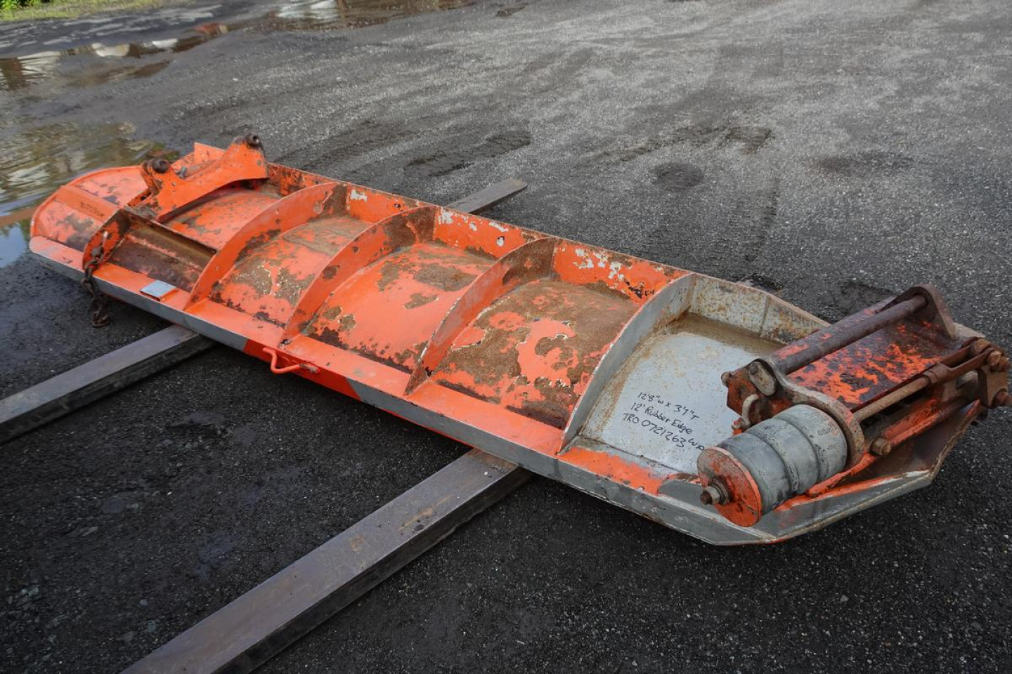 Dump truck attachment showing orange snow plow scoop with hydraulic cylinder and mounting arms.