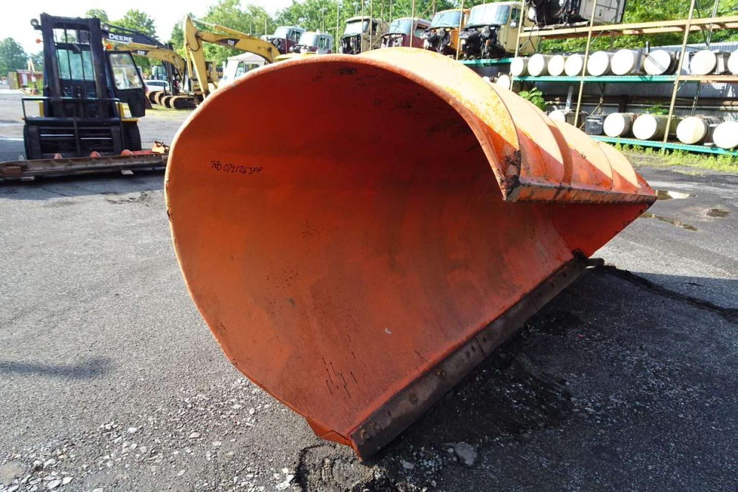Front view of an orange dump truck snowplow attachment bucket showing wear and curved leading edge.