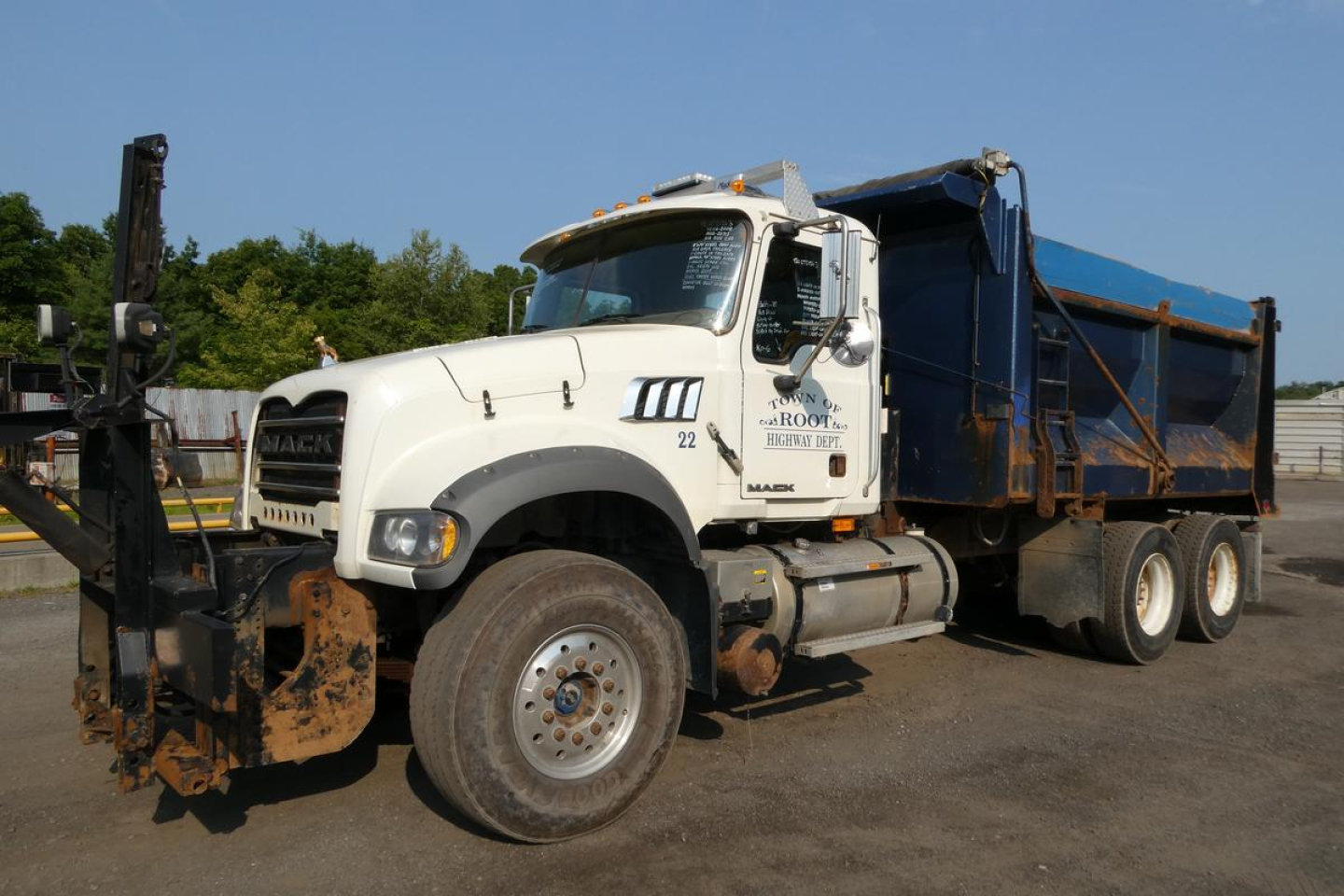Mack GU713 dump truck in service condition showing front grille, cab, and blue dump bed with chains, side text visible
