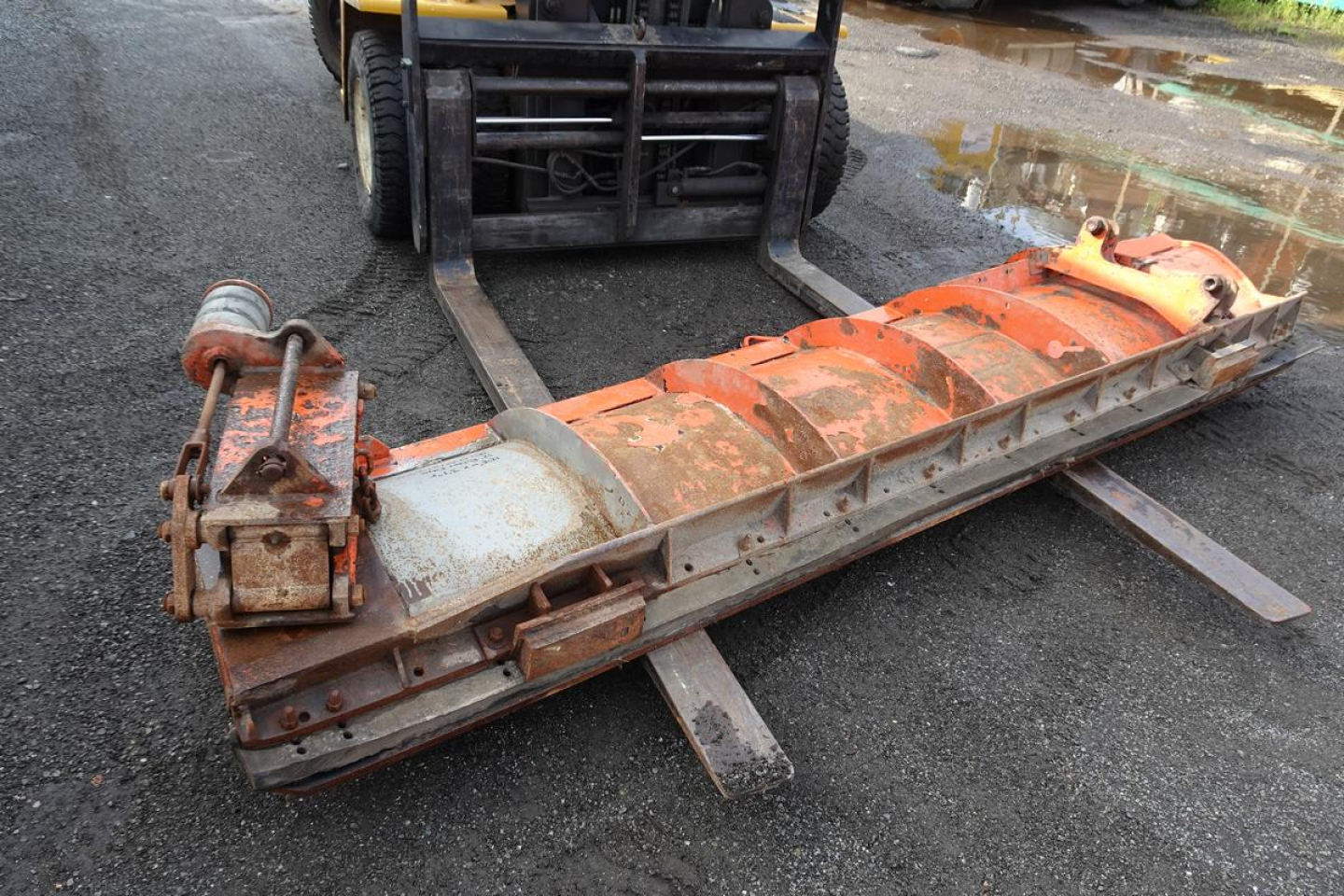 Mack GU713 frame or attachment lying on ground with forks and hydraulic component attached, orange-brown paint and rust visible