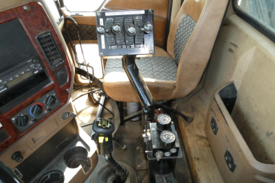 Cab interior of a 2008 Mack GU713 dump truck showing a center console with gauges and control panel, steering column, gear shifter, and passenger seat.