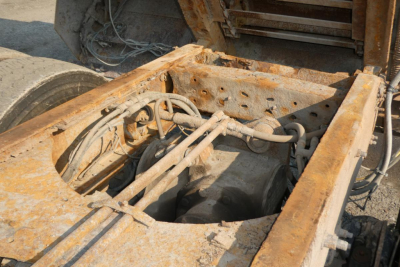 Frame rails and engine bay of a 2008 Mack GU713 dump truck chassis showing exposed drivetrain and wiring with rusted metal.