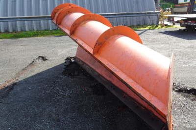 Orange Mack GU713 snow plow blade attachment viewed from the side showing curved segments and cutting edge.