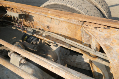 Dump truck frame undercarriage showing rusted beams and suspension components.