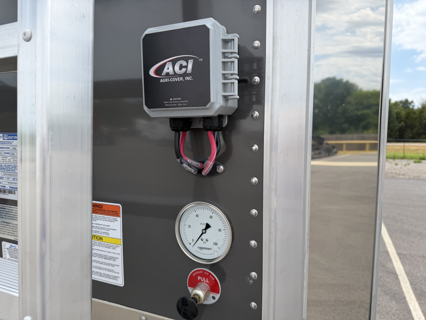 Hopper trailer near bulkhead with ACI controller and gauge showing 0-? psi; side panel hardware and warning labels visible.