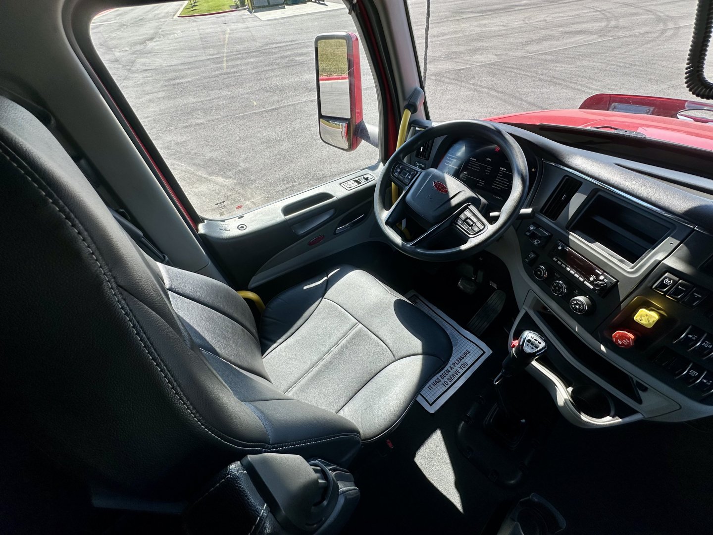 Peterbilt 567 cabin interior with steering wheel, dashboard controls, and driver seat in view.