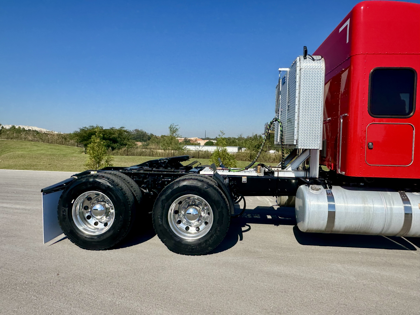 Peterbilt 567 tractor truck chassis showing dual rear axles and fuel tanks with red sleeper cab.